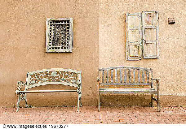 Two benches against an adobe wall located in Santa Fe  New Mexico.