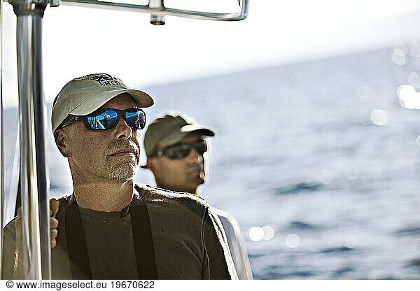two boaters with sunglasses looking off into the ocean