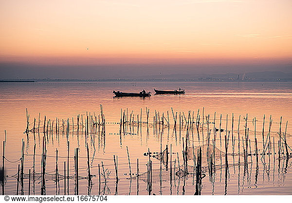 Two boats and fishing nets at the Albufera sunset against the light