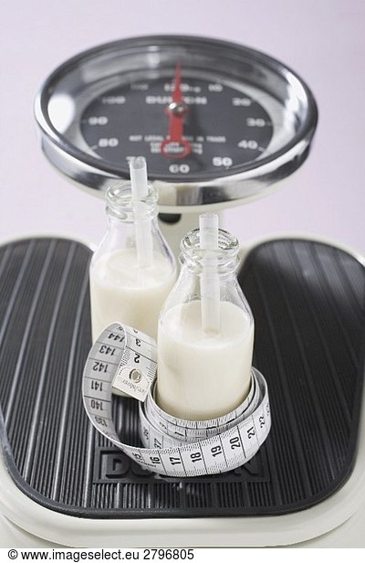 Two bottles of milk with tape measure on scales