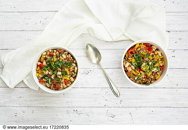 Two bowls of bean stew with bell peppers  quinoa and parsley
