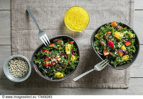 Two bowls of kale salad with bell peppers and orange