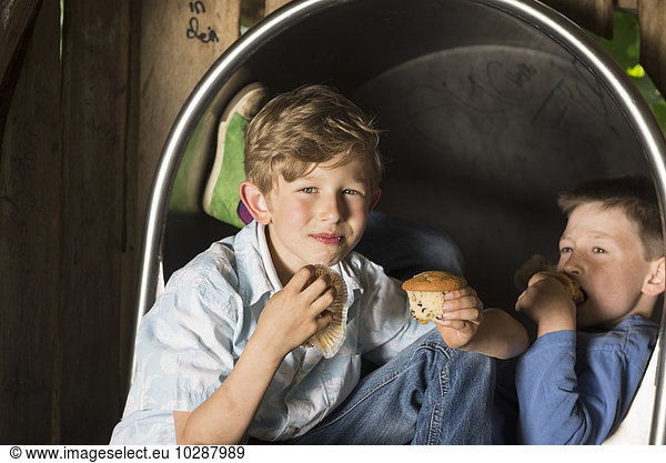 Two boys eating muffins in playground  Munich  Bavaria  Germany