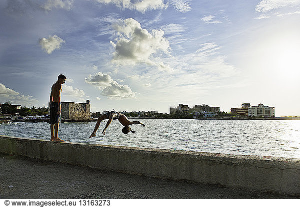 Two boys playing and diving from harbor wall  Havana  Cuba