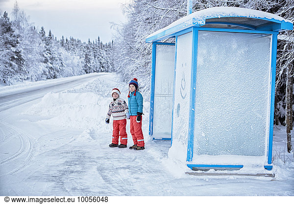 Two brothers waiting at snow covered bus stop  Hemavan Sweden