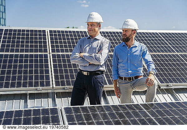 Two businessmen  donning hardhats  exude confidence as they stand amidst a field of solar panels