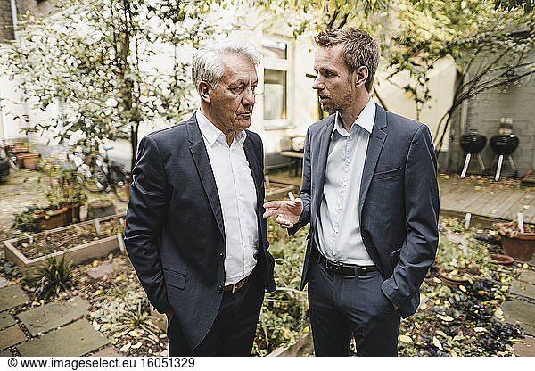 Two businessmen standing office backyard  discussing