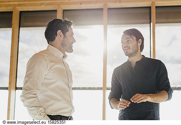 Two businessmen talking at the window in office