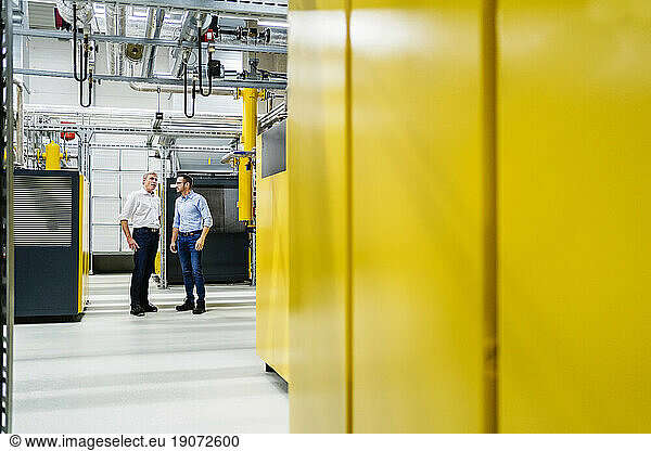 Two businessmen talking in factory