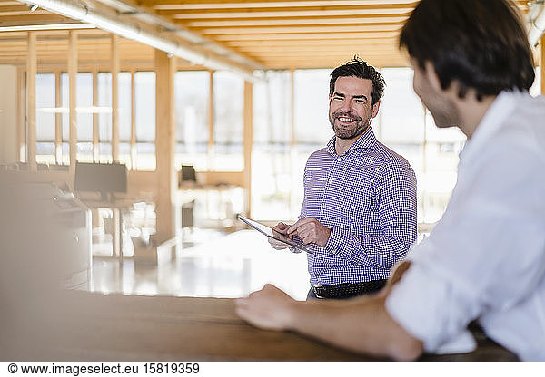 Two businessmen talking in wooden open-plan office