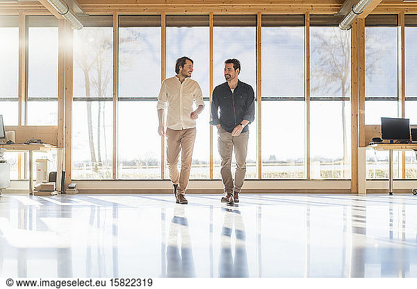 Two businessmen talking in wooden open-plan office