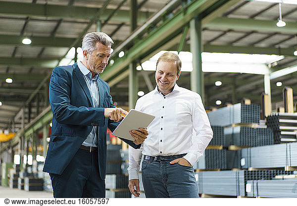 Two businessmen using tablet in a factory