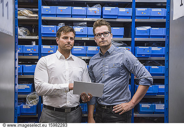Two businessmen using tablet in storehouse of a factory
