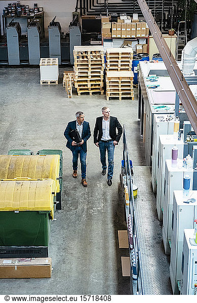 Two businessmen walking and talking in a factory
