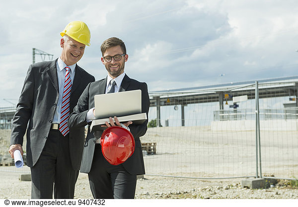 Two businessmen with hard hats on construction site