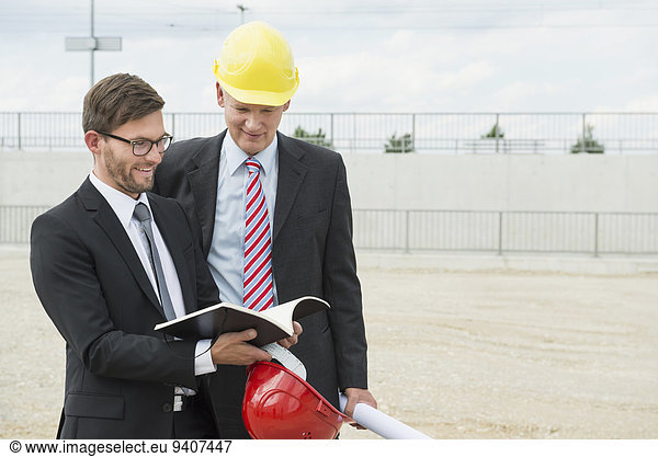 Two businessmen with hard hats on construction site