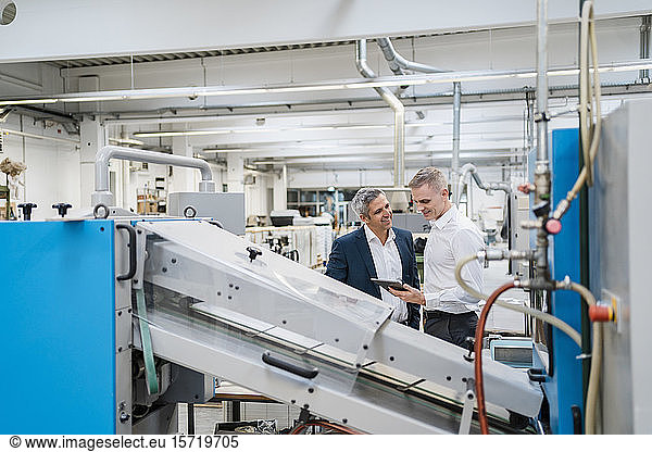 Two businessmen with tablet talking in a factory