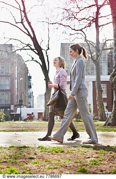 Two businesswomen walking on path in park