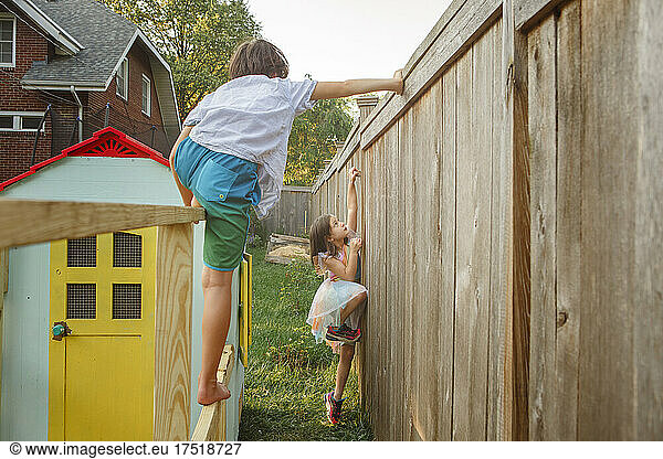 Two children climb and play together in backyard