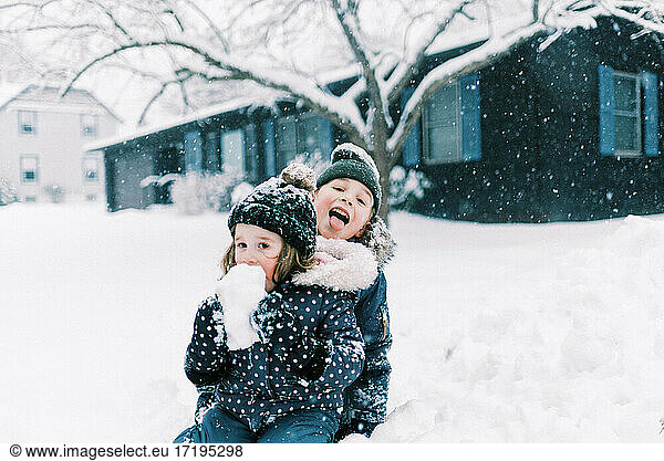 Two children eating snow and playing together in nor'easter storm