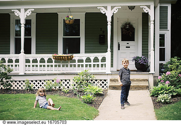 Two children in front of their house