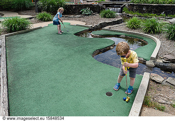 Two children play mini golf.