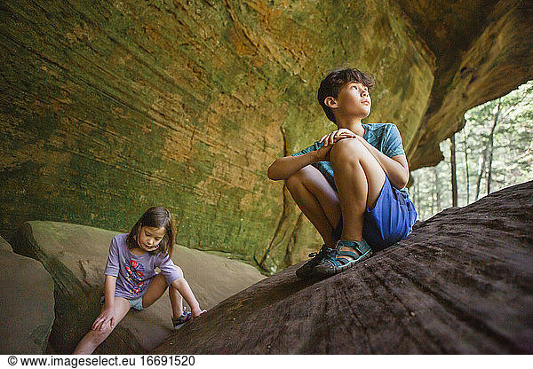 Two children play together on a rocky outcrop in a sandstone gorge