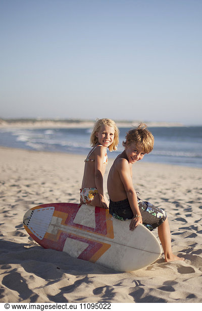 Two children sitting on bodyboard at the beach  Viana do Castelo  Norte Region  Portugal