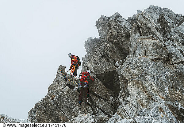 Two climbers descending exposed ridge on icy day