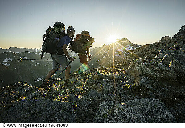 Two climbers hiking at sunset with mountains in background  Canada