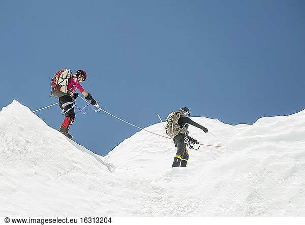 Two climbers in snow on a mountain  roped together.