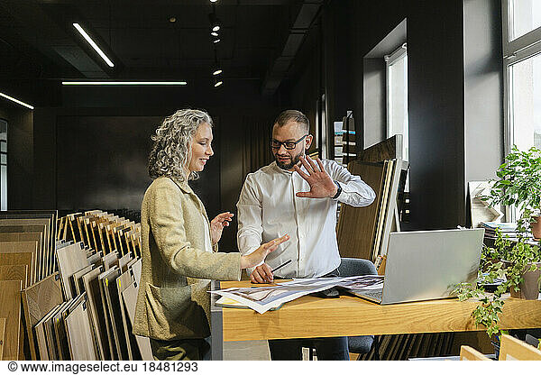 Two colleagues talking and gesturing in architect's office