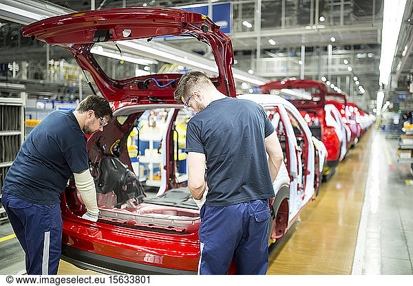 Two colleagues working in modern car factory