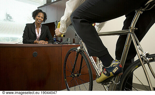 Two corporate executives have a meeting while one rides his bicycle in the office in Santa Clara  California.