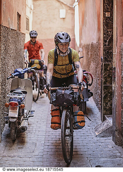 Two cyclists ride their bikes through the narrow streets of Marrakesh