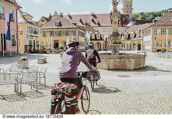 Two cyclists riding his bikes in a square in Bavaria  Germany