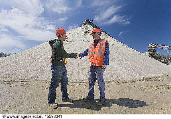 Two engineers shaking hands at a gravel and asphalt plant