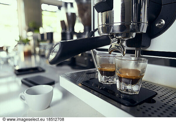 Two espresso shots being pulled into glasses from a machine.
