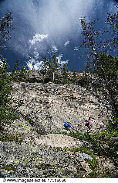 Two female backpackers cross a rock slab