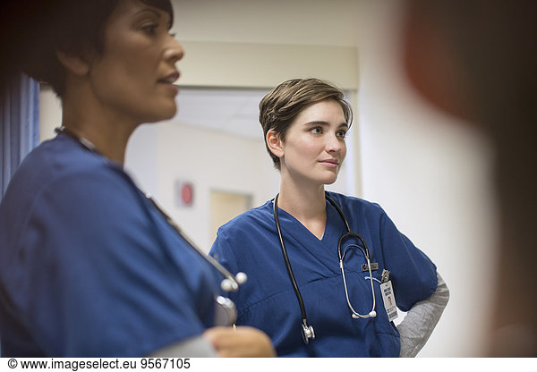 Two female doctors wearing navy blue scrubs  talking in hospital