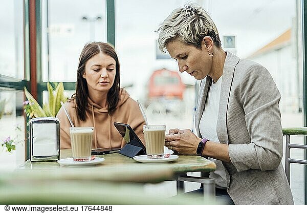 Two female friends drinking coffee and enjoying time in the cafe at railway station