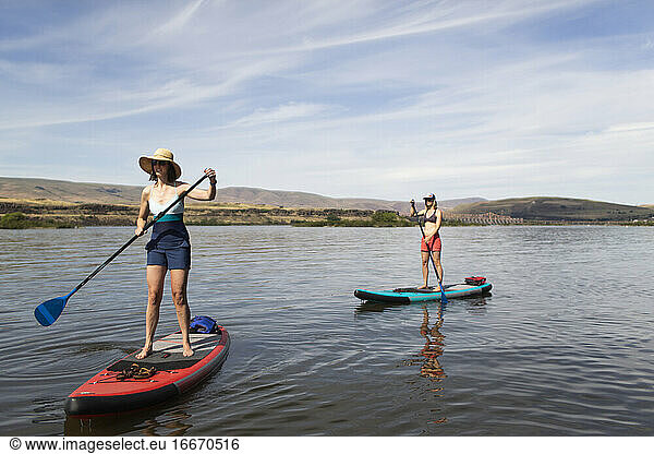 Two female friends enjoy their SUPs on the Columbia River in Oregon.