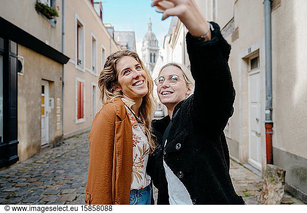 Two female friends taking a selfie in a french touristic town