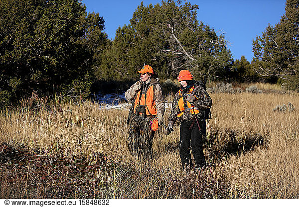 Two female hunters hike in a meadow in Colorado