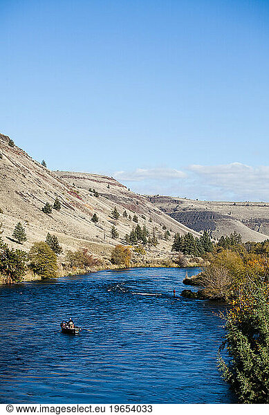 Two fisherman float down a river with mountains in the distance on a sunny day outside Bend  Oregon.