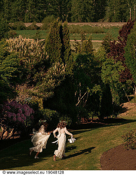 two flower girls run in sunny garden wedding.