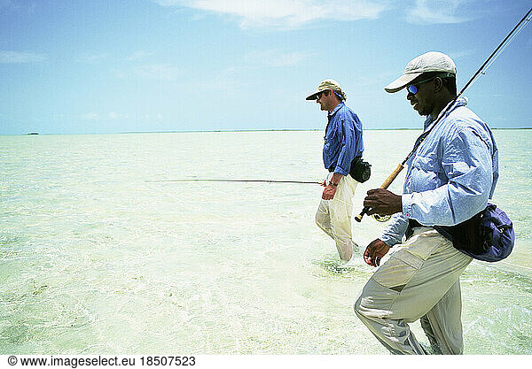 Two fly-fishermen wade the saltwater flats of the Bahamas.