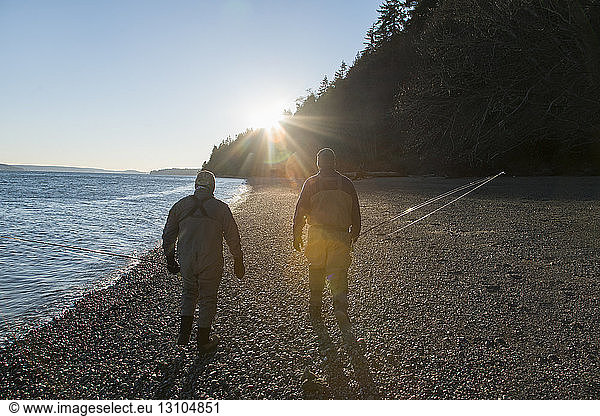 Two fly fishermen walking on a beach close to sundown