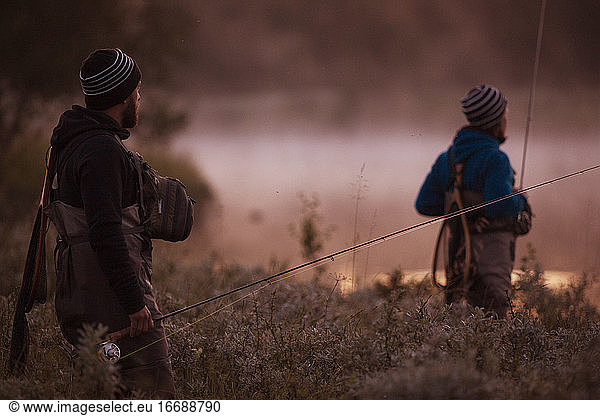 Two fly fishers looking at the river in the morning mist