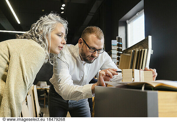 Two focused colleagues working on wooden model in architect's office together